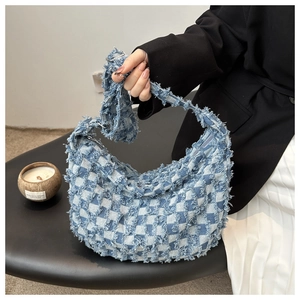 Detail of blue and white checkered denim bag with fringe edges and silver zipper