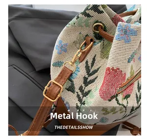 Detailed macro view of the gold-tone hardware hook and leather strap on a floral bucket bag