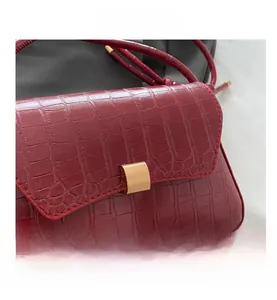 Détail du sac à bandoulière bordeaux motif crocodile avec fermoir doré rectangulaire