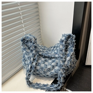 Detailed view of checkered denim shoulder bag with distressed frayed edges and zipper