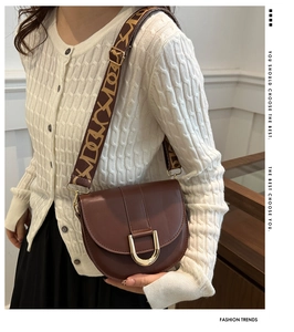 Brown saddle bag with golden horseshoe buckle and wide geometric jacquard strap