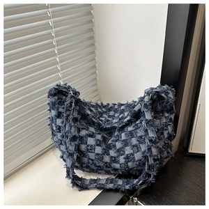 Close-up of denim patchwork tote featuring frayed edges and blue checkered pattern