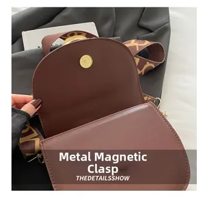 Detailed view of the gold magnetic metal clasp on a premium brown leather saddle bag