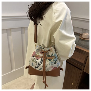 Detailed close-up of a floral canvas bucket bag showing ethnic patterns and leather straps