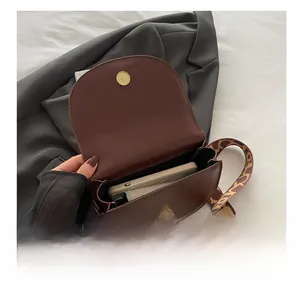 Detail view of the spacious interior of a matte brown saddle bag with its wide shoulder strap