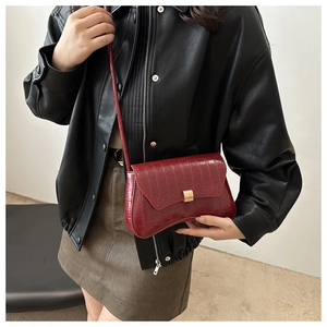Détail d'un sac porté épaule rouge foncé à motif crocodile et fermoir doré chic