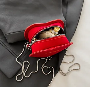 Détail de la capacité intérieure d'un sac bandoulière rouge en daim en forme de cœur à chaîne