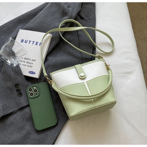 Flachbild von grün-weißer Eimertasche auf grauem Anzug mit Lifestyle-Requisiten und Licht