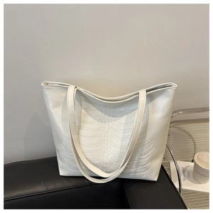 Detalle de bolso tote blanco con relieve 3D de costillas y correas finas para hombro