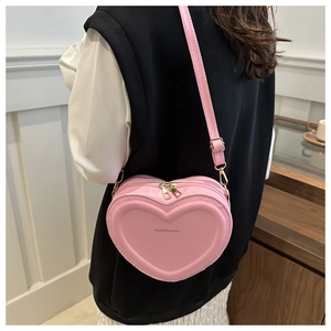 Pink heart-shaped crossbody bag shown from a side view on a model for scale and fit