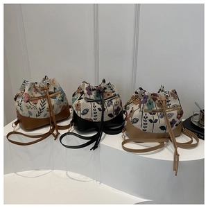 Detailed close-up of three floral jacquard bucket bags with drawstring and leather base