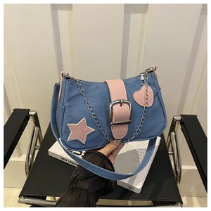 Detalle del bolso de hombro denim azul con parches de estrellas rosas y cadena de plata