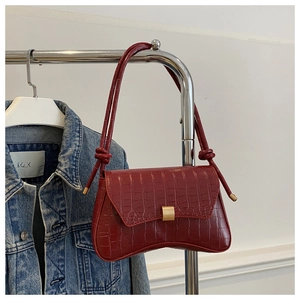 Détail du sac rouge foncé motif crocodile avec boucle dorée et bandoulière nouée