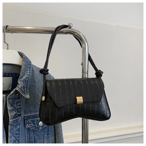 Détail du sac à main noir motif crocodile avec boucle magnétique dorée chic