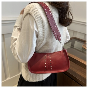 Detail der roten Vintage Baguette Tasche mit Nieten und breitem Gurt an einem Modell