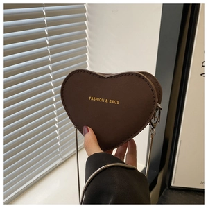 Détail du sac bandoulière marron en forme de cœur avec texte doré et chaîne fine