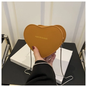 Vue macro d'un sac bandoulière en forme de cœur en cuir camel avec bandoulière chaîne