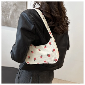 Modella che indossa una borsa a spalla in velluto bianco con motivo a fragole