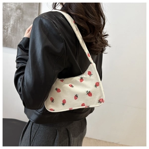 Gros plan du sac à bandoulière en velours côtelé blanc aux motifs de fraises rouges