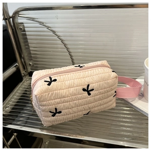 Détail de la trousse de maquillage rose matelassée avec broderie papillon noire et fermeture éclair