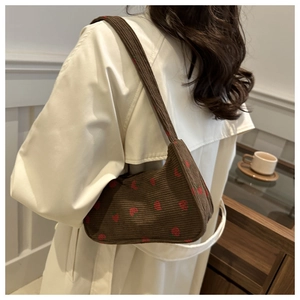 Détail rapproché du sac à bandoulière en velours côtelé avec broderie fraise rouge