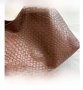 Gros plan sur le sac cabas en cuir marron montrant le motif de tissage à carreaux