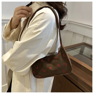 Détail du sac sous le bras en velours côtelé marron avec broderie fraise sur l'épaule