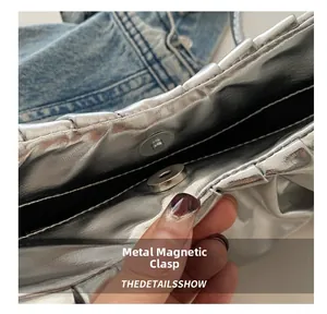 Detail showing the magnetic snap closure and silver pleated texture of the crescent bag