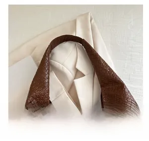 Détail d'un sac hobo en cuir tressé marron avec un design de texture intrecciato