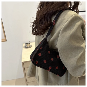 Gros plan du sac porté épaule en velours côtelé noir avec broderie de fraises rouges