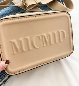 Detail der MICMID-Buchstabenprägung auf einer beigen Kunstleder-Umhängetasche