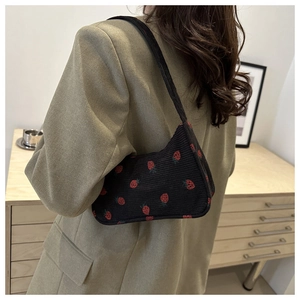 Détail du sac à bandoulière en velours côtelé noir avec motif fraise rouge brodé