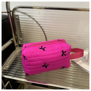 Gros plan détaillé de la trousse de maquillage matelassée fuchsia avec broderie nœud noir