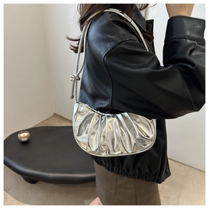 Detail of silver metallic crescent bag with ruched texture and knotted strap design