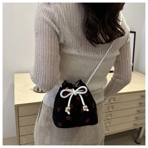 Detail of black corduroy bucket bag with strawberry embroidery and white drawstring