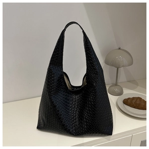 Gros plan d'un sac cabas noir en cuir tressé montrant un savoir-faire artisanal précis