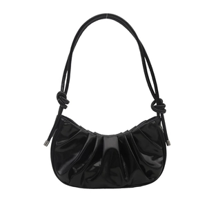 Glossy black pleated crescent shoulder bag with knot detail in a minimalist aesthetic