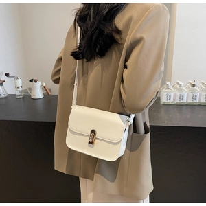 Détail du sac à bandoulière carré blanc avec fermoir rotatif en métal doré et lanière