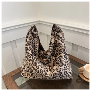 Detail van canvas shopper met luipaardprint en bruine leren riemen op een houten tafel