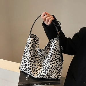 Stijlvolle hobo-tas met luipaardprint en zwarte leren riemen in een modieuze setting