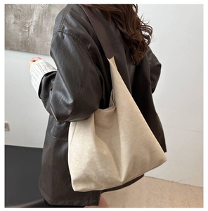 Close-up of a large beige canvas hobo bag with contrast coffee brown shoulder strap