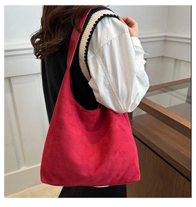 Gros plan d'un sac cabas rouge en daim montrant sa texture mate et son design minimaliste