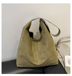 Detail of olive green suede tote bag showing soft texture on a black leather bench