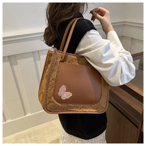 Détail latéral d'un sac cabas en fausse fourrure et cuir PU marron avec broderie papillon rose