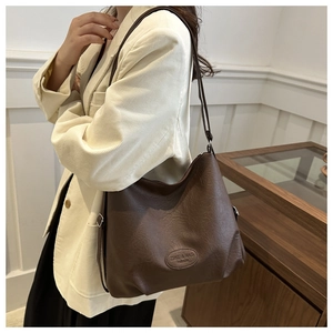 Close-up of brown lychee-textured leather tote bag worn with a white corduroy blazer