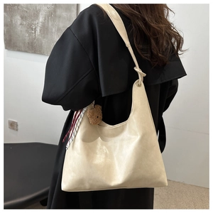 Detalle del bolso tote crema con colgante de oso y pañuelo decorativo de cuadros suaves