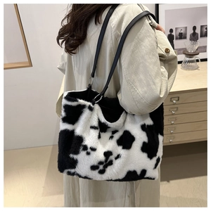 Detail of plush cow print tote bag worn on shoulder over a beige autumn coat