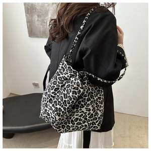 Detailed side view of large leopard print tote bag with thick shoulder straps worn by model