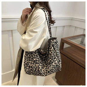 Close-up of a large leopard print corduroy tote bag worn on a woman's shoulder