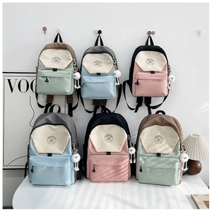 Primer plano de mochilas escolares en contraste de colores con colgantes de felpa